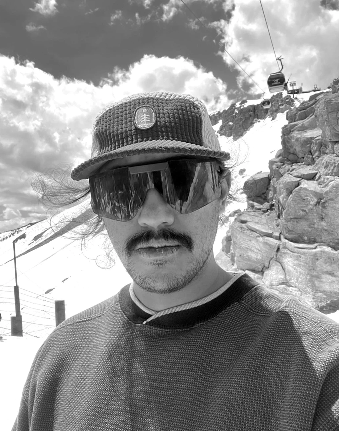Austin Hunt in the mountains with snow and a lift in the background.
